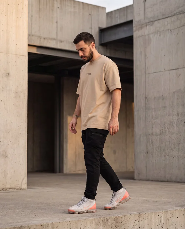 Oversized t-shirt in sand on a model in front of concrete architecture